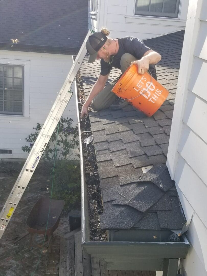 A man is cleaning the gutter of his house.