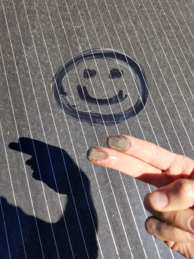 A person touching their finger to the shadow of a smiley face.