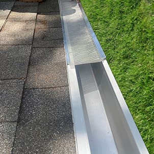 A gutter that is being installed on the side of a house.
