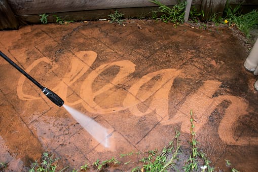 A person using a power washer on the ground.