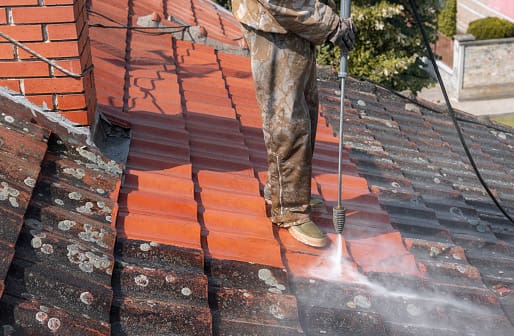 A man is cleaning the roof of a house.