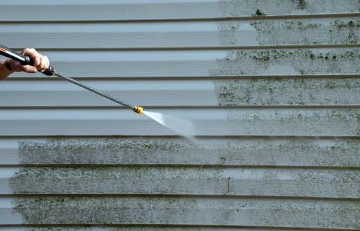 A power washer cleaning the side of a house.