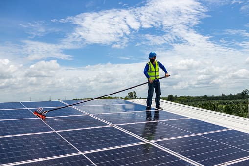 A man is cleaning the roof of a solar panel.