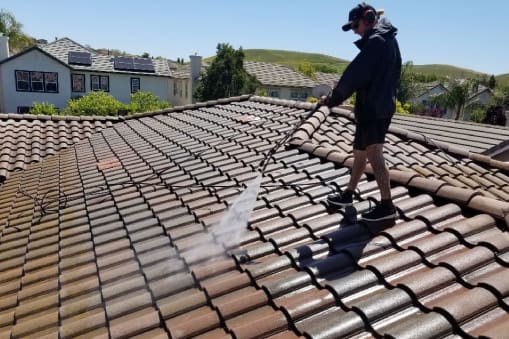 A man is cleaning the roof of his house.