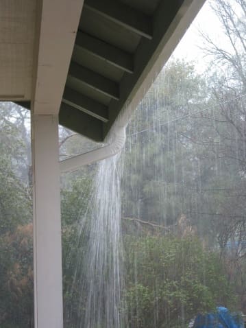 A rain shower pouring into the air from under a porch.