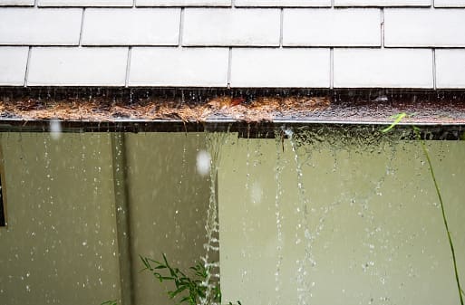 A rain gutter with water pouring out of it.