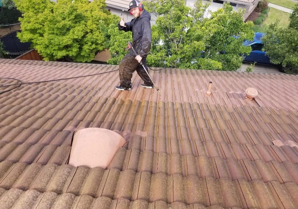 A man walking across the roof of his house.